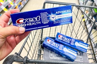 hand holding crest toothpaste above shopping cart with two identical toothpastes