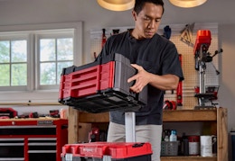 man carrying the red and black Craftsman Versastack tool chest