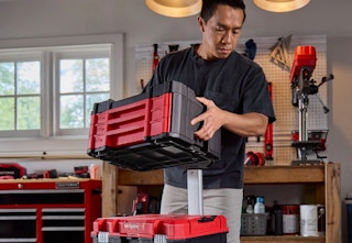 man carrying the red and black Craftsman Versastack tool chest