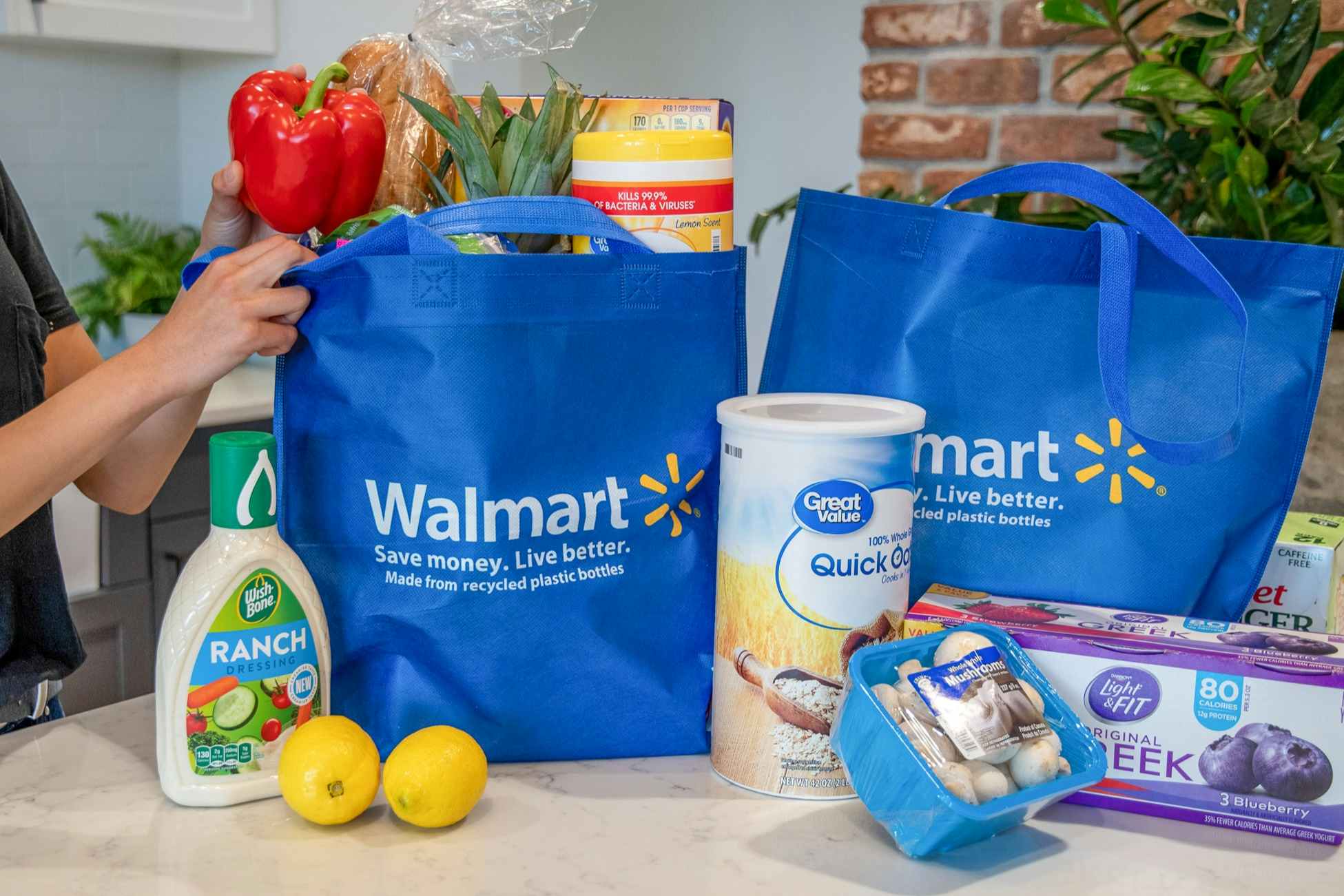 A woman pulling groceries out of Walmart reusable grocery bags.