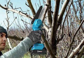 person using the mini chainsaw on a branch