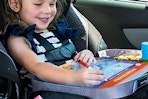 child using busy book in car