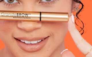 a person holding a tube of brow serum
