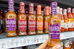 hand holding a bottle of tabanero hot sauce in walmart aisle