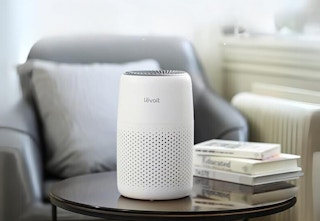 air purifier on round coffee table with books in front of armchair in living room