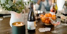 best cheap champagne - A bottle of Good Clean Spumante champagne on a table with a candle, some glasses, and a bowl of fruit