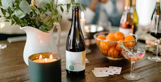 best cheap champagne - A bottle of Good Clean Spumante champagne on a table with a candle, some glasses, and a bowl of fruit