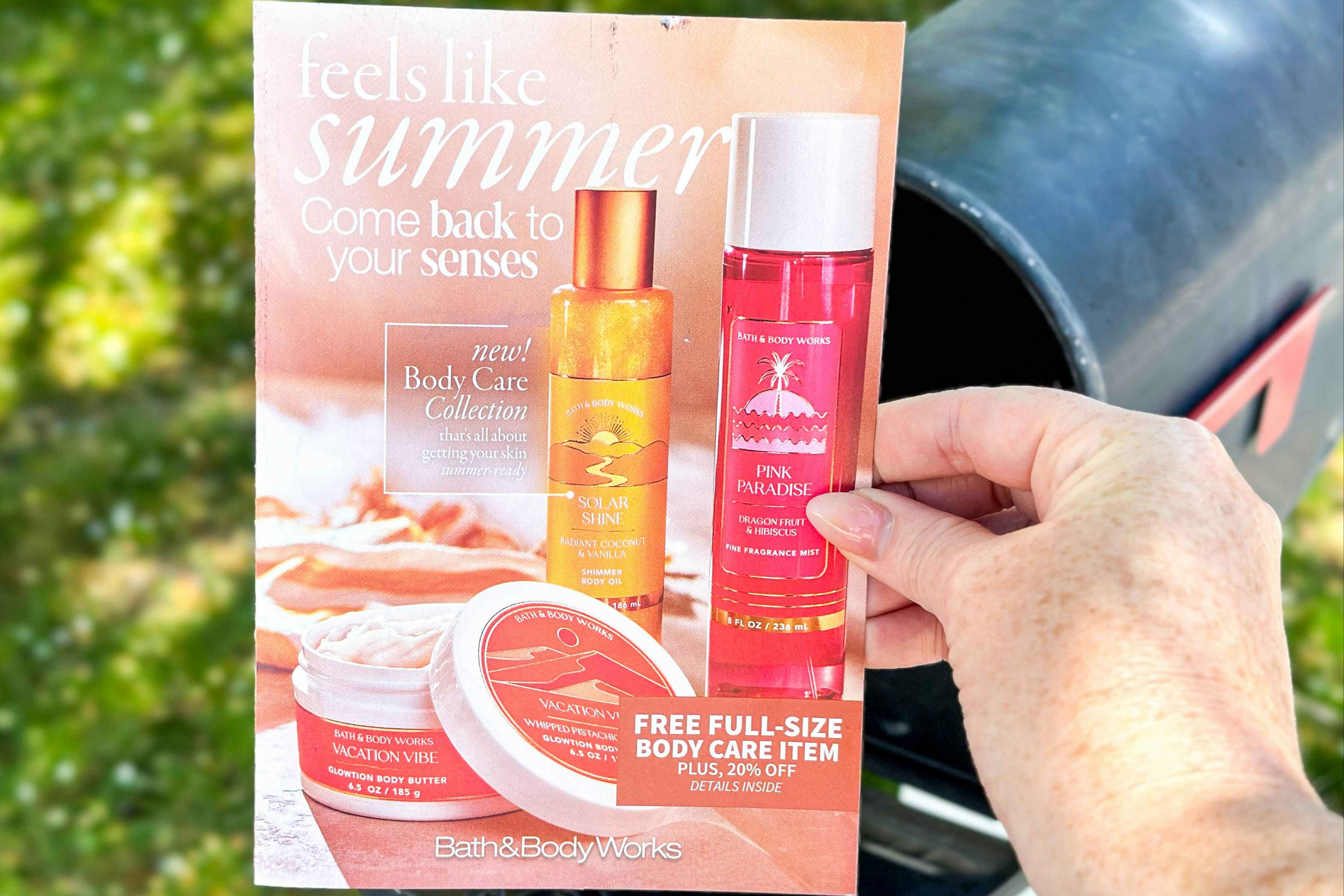 bath and body works mailer being held in front of mailbox 