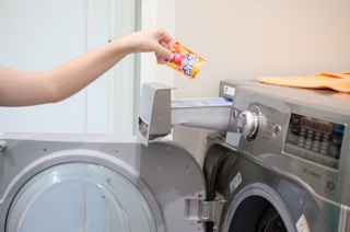 someone pouring KoolAid into a washing machine