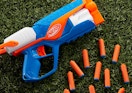 a Nerf blaster on grass with orange darts