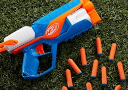 a Nerf blaster on grass with orange darts