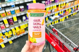 person holding a bottle of natures bounty vitamins over a cvs cart