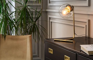 A bronze desk lamp illuminating the area on a desk.