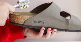 a person cleaning Birkenstocks with a soft brush