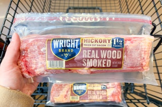 hand holding a pack of wright bacon over shopping cart
