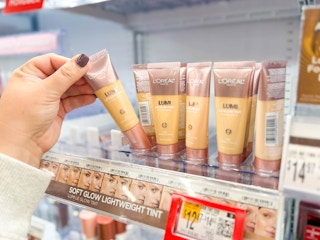 hand holding a loreal lumi foundation with others on walmart shelf