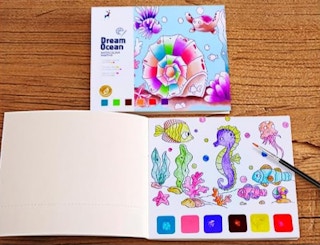 a book with watercolor paint and ocean animal picture on a table