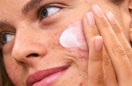 a person rubbing on face cream