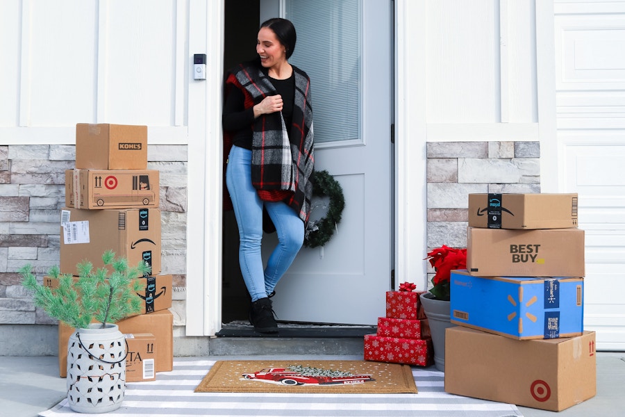 a woman going out to her house looking at a lot of packages 