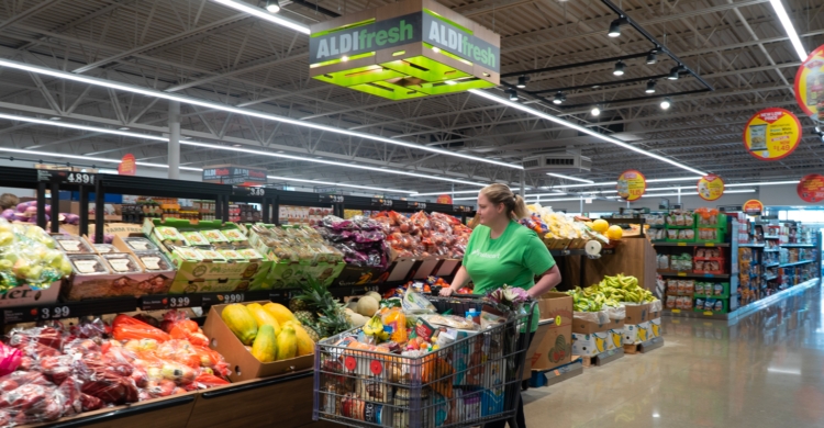 an instacart shopper peruses the produce at aldi