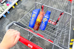 hand pushing a CVS shopping cart with Coppertone sunscreens