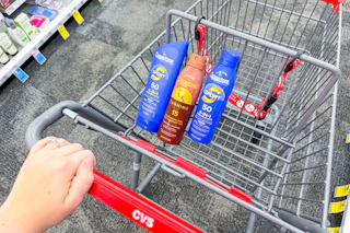 hand pushing a CVS shopping cart with Coppertone sunscreens