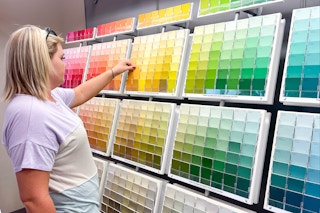 woman looking at a large wall of paint colors and swatches