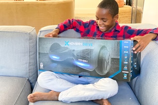 A boy holding a Hover-1 Hoverboard toy.