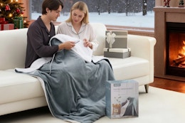 lifestyle image of a couple sitting under a heated blanket on a couch