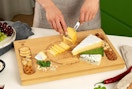 a person cutting cheese on a charcuterie board