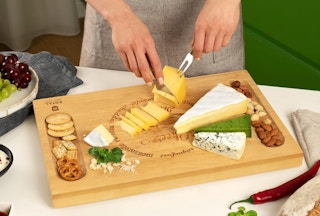 a person cutting cheese on a charcuterie board