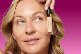 woman holding concealer up to face