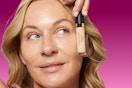woman holding concealer up to face