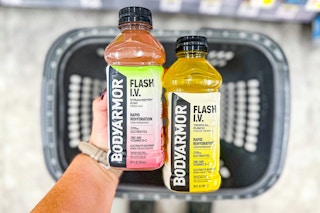 person holding 2 body armor drinks over a basket