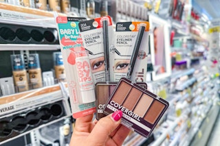 hand holding one Maybelline Baby Lips, two Revlon eyeliners, and two Covergirl eye palettes