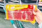 hand holding a pack of oscar mayer bacon