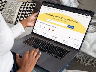 A person using a laptop looking at the GoodRx.com homepage