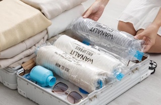 rolled up vacuum bags in a suitcase with sunglasses and clothes