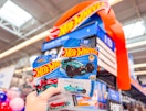 hand holding two packages of Hot Wheels cars