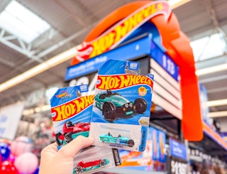 hand holding two packages of Hot Wheels cars