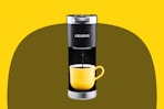 Stock image of the Keurig Mini Coffee maker in back with a yellow coffee mug
