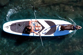 Woman and dog on the SereneLife XL Inflatable Stand Up Paddle Board.