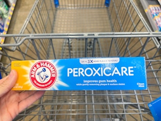 A box of Arm & Hammer Peroxicare toothpaste held out in front of a shopping cart