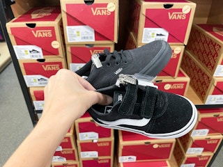 Two different types of Vans shoes held out in front of Vans boxes.