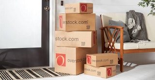 A tall pile of Overstock.com packages outside of a front door