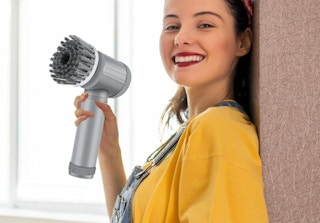 a person holding a handheld electric spin scrubber 