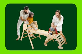 A man and woman help a baby and a toddler play on the Pikler Triangle Set, which is set in the bridge arrangement