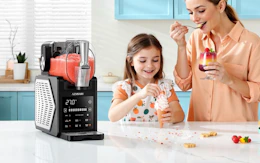 a mom and daughter eating ice cream next to a slushie machine