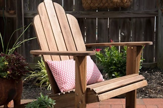 Linon Woodstock Adirondack Lounge Chair on a patio with a red pillow in the seat.