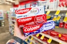 hand holding three colgate toothpastes